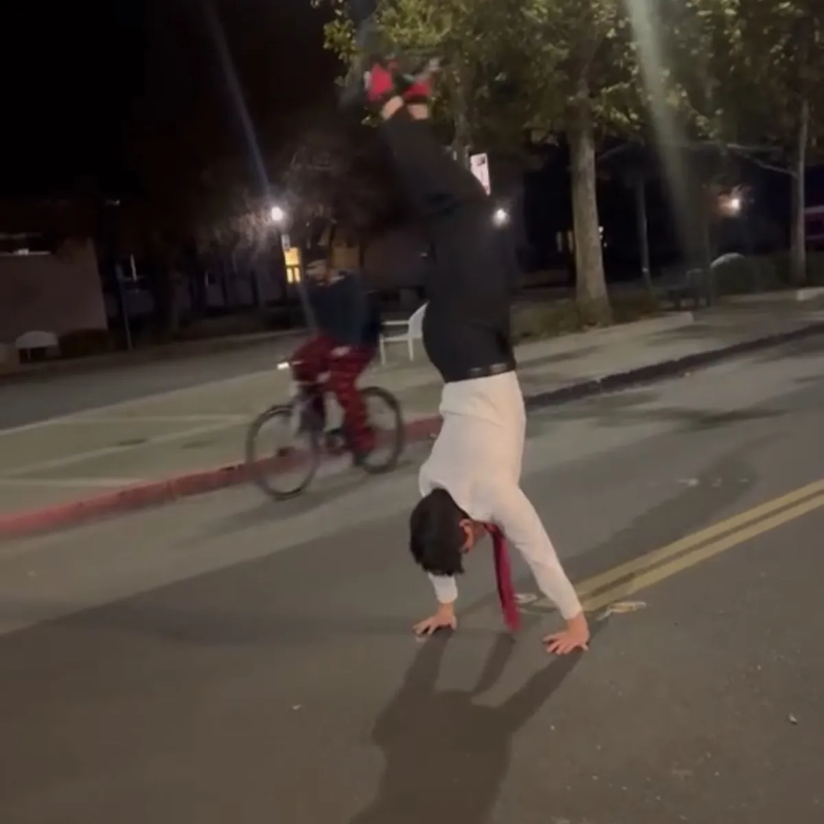Jayden doing a handstand in the street at night, still in his showcase shirt and tie